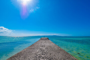 Tropical island's concrete pier with beautiful ocean. Blue clear ocean with corals with blue sky,...