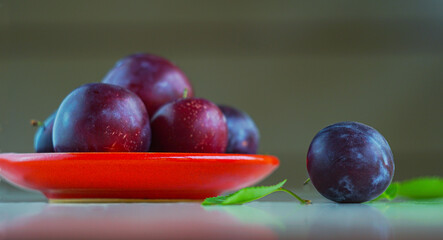 Plums in a red bowl