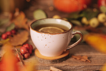 A cup of hot tea with lemon on an autumn background. Autumn and fall postcard. Thanksgiving day or halloween concept.