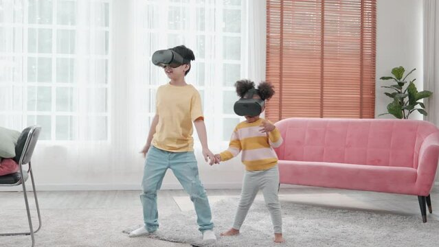 Portrait of enjoy happy kids using VR metaverse gaming technology in living room at home. Child smiling and having fun using glasses of technology virtual reality headset playing sport gaming