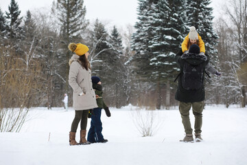 Happy family playing and laughing in winter outdoors in the snow. City park winter day.