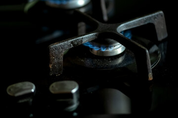 Detail of burning gas on the stove, rising gas prices,detail of a black gas stove, price growth, dirty black oven with a burn gas