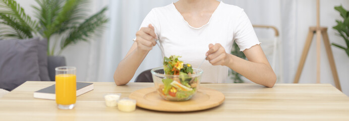 Fototapeta na wymiar Asian woman eating salad on the dining table smiling and happy, Vegetable salads are rich in vitamins and minerals, Fat-low-calorie and high-fiber diets, Health care by eating fresh vegetables.