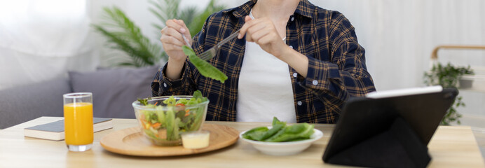 Asian woman eating salad on the dining table smiling and happy, Vegetable salads are rich in...