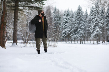 Outdoor portrait of handsome man in coat and scurf. Bearded man in the winter woods.