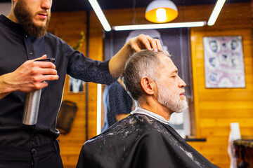 pensioner man with gray beard with hairstylist in trendy spa men grooming salon