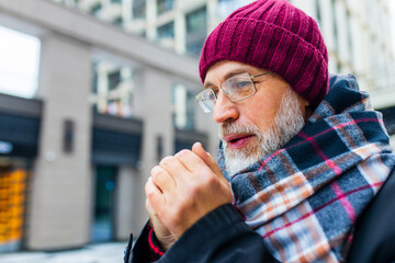 mature man trying to warm my hands in winter market in city town