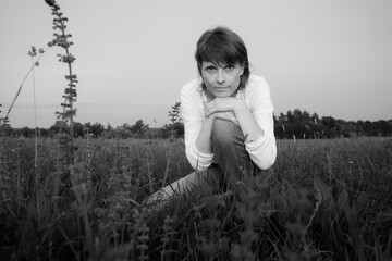 Eine junge Frau sitzt im Sommer im Gras