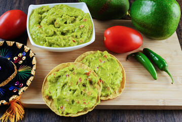 Guacamole served on a white plate on a wooden table. Guacamole ingredients.