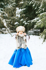 Fototapeta na wymiar portrait of beautiful cute little Asian girl in fur coat and fur hat standing in snowy forest in winter, winter holidays and having fun, Christmas vacation