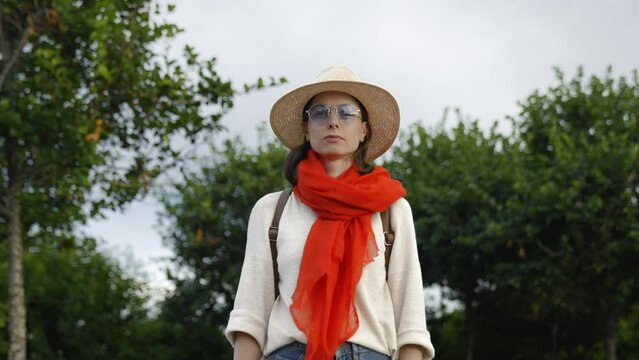 Serious woman in a hat looking at camera, outdoors
