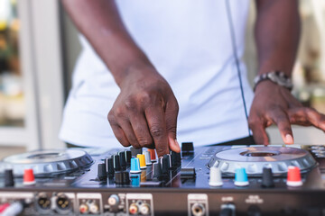 View of Dj mixer and vinyl plate with headphones on a table with african american DJ playing on...