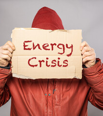 Man holding cardboard sign with Energy Crisis text in winter coat freezing in the cold