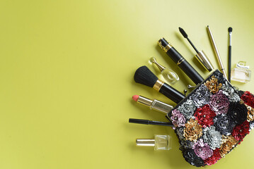make up bag with cosmetics and brushes on green background. top view. copy space.
