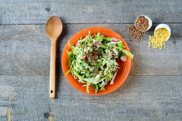 Fresh salad in orange plate on wooden table