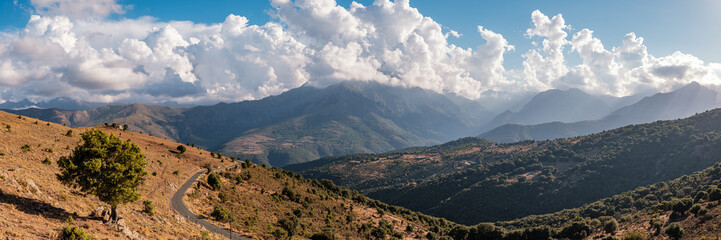Obraz premium Panoramic view of afternoon sunshine on the 2389 metre peak of Monte Padro and surrounding mountains in the Balagne region of Corsica