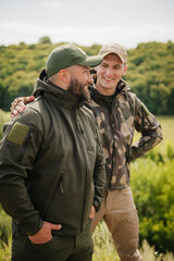Two guys hunters fishers wearing tactical hunter gear happy meet each other and enjoy nice natural outdoor landscape