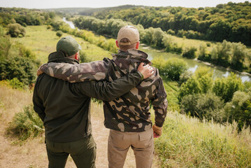 Two guys hunters fishers wearing tactical hunter gear happy meet each other and enjoy nice natural...