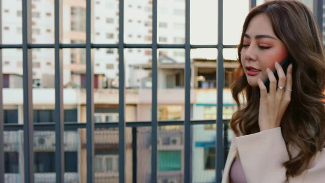 A woman having fun doing talking on the phone with friend at the rooftop.