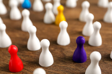 Colorful pawns on wooden table, closeup. Social inclusion concept