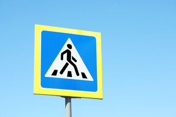 Post with Pedestrian Crossing traffic sign against blue sky on sunny day. Space for text