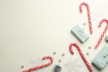 Flat lay composition with candy canes and Christmas decor on beige background. Space for text