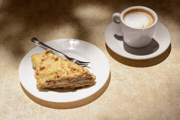Piece of delicious cake and coffee on beige table
