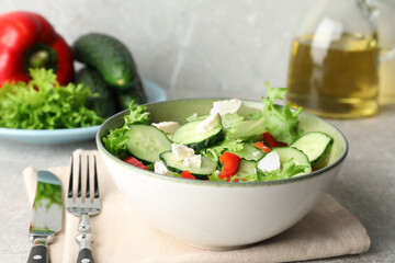 Delicious salad with cucumbers, red bell pepper and feta cheese in bowl served on light grey table