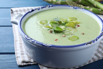 Delicious asparagus soup on blue wooden table, closeup