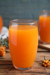 Sea buckthorn juice and fresh berries on wooden table, closeup