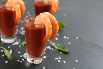 Delicious shrimp cocktail with tomato sauce served on black table, closeup. Space for text