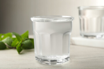Glass of soda water and mint on white wooden table