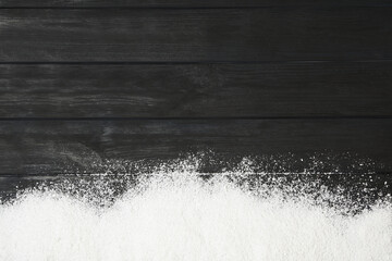 Artificial snow on black wooden background, top view with space for text. Christmas decor