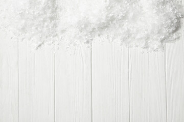 Snow and space for text on white wooden background, top view. Christmas season