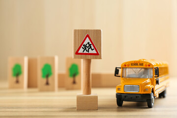 Traffic sign Attention children crossing street and toy bus on wooden table. Passing driving...