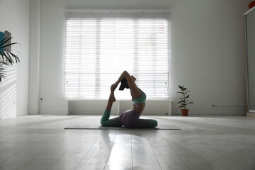 Woman practicing one legged king pigeon asana in yoga studio. Eka pada rajakapotasana pose