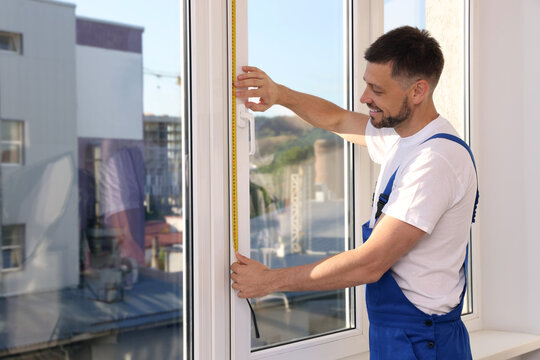 Worker measuring plastic window indoors. Installation process