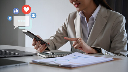 Asian businesswoman hands typing on mobile phone with notification icons of like, message and comment