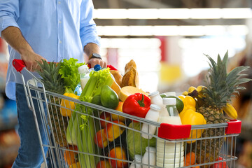Man with shopping cart full of groceries in supermarket, closeup © New Africa