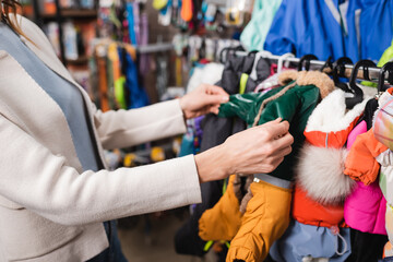 Fototapeta na wymiar Cropped view of woman choosing animal jackets in blurred pet shop