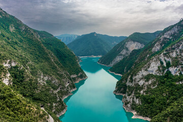 Piva Lake - Amazing Mountain View in Montenegro / Alps Landscape - turquoise blue water on Balkan with main Mountain in the middle - wide aerial drone shot - obrazy, fototapety, plakaty
