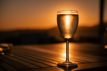 Traditional house white wine served in tavern, traditional greece drink, mazing sunset as background