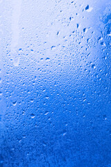 Texture of ice on the glass, icy surface of a frozen window, background, blue monochrome.