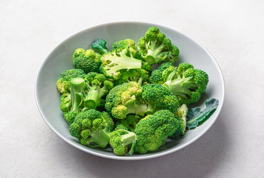 Broccoli in a plate on a gray wooden background. Cooking broccoli. Side view, close-up. Healthy food