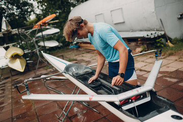 Sportsman single scull man rower prepare to competition with boat.