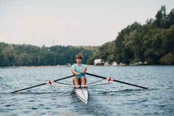 Sportsman single scull man rower rowing on boat.
