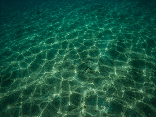Fototapeta na wymiar Underwater picture of sand sea bottom with waves refraction visible on the sea floor