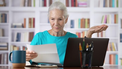 Stressed senior woman holding letter troubled with domestic bills, bad news.