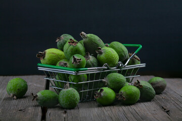 feijoa fruits in a supermarket basket on dark background