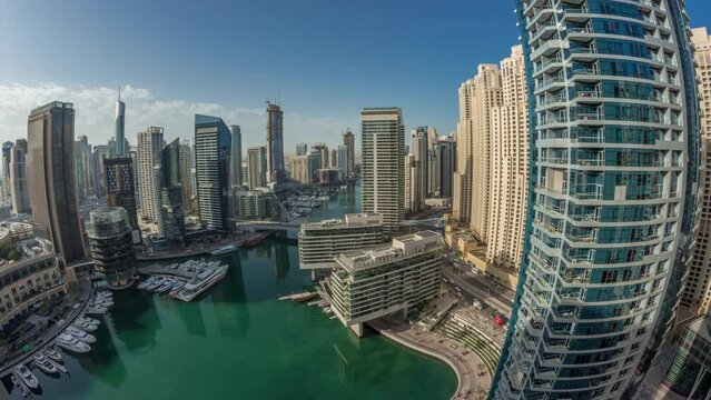 Panoramic aerial view to Dubai marina skyscrapers and jbr towers around canal with floating boats morning timelapse during sunrise. White boats are parked in yacht club
